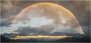Fotokarte vollständiger Regenbogen über der Magadinoebene bei Locarno (Tessin), Gewitterwolken, Panoramaformat